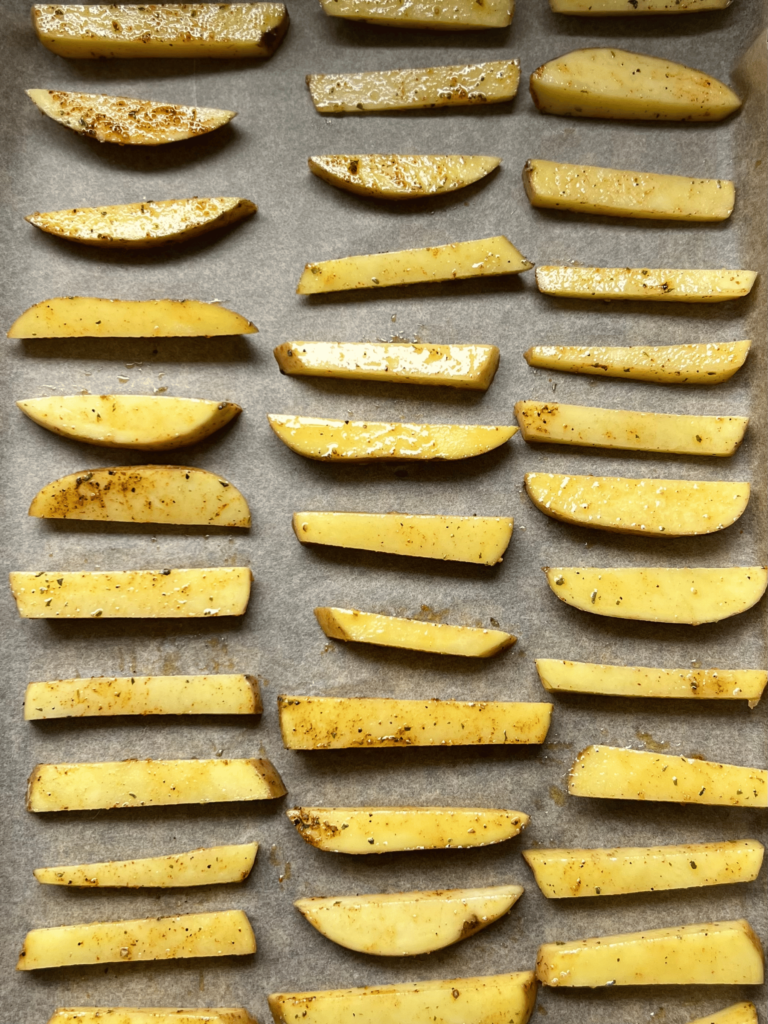 baked homemade french fries laid out on parchment paper